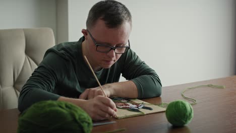 hombre caucásico adulto con síndrome de down haciendo una artesanía.