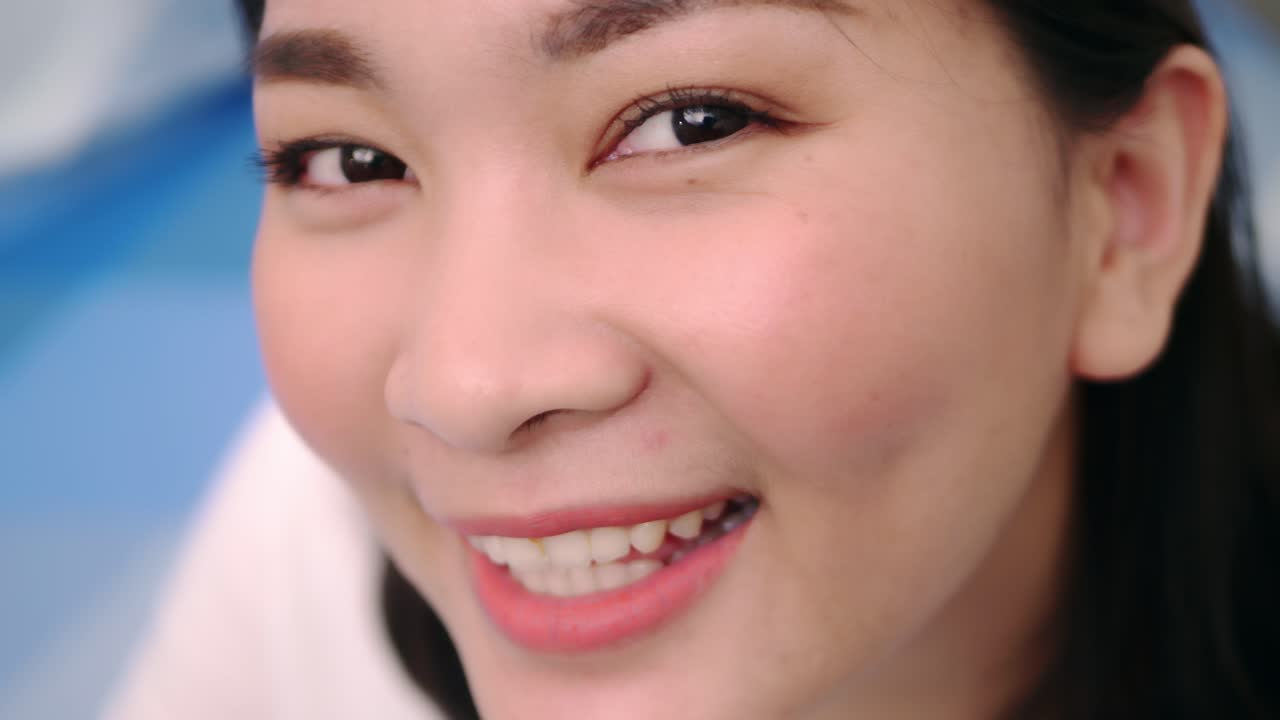 아름답고 웃고 있는 아시아 여성들은 휴일에 혼자 전문적인 초상화를 취한 카메라를 바라보며 극도로 자신감 있는 젊은 얼굴을 하고 맑은 빛, 슬로우 모션 장면으로 휴식을 취합니다.