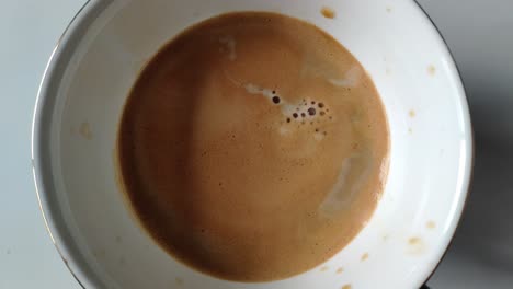 a cup of coffee being poured with milk, showing a smooth texture and froth