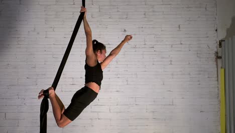 aerial yoga instructor starting the exercise routine while wearing black sportswear, fit woman