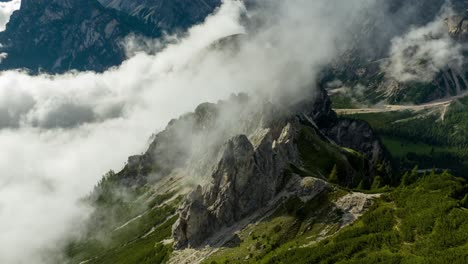 aerial hyperlapse of fog drifting over and around pointed rocky peaks in the dolomite mountains of italy during the day