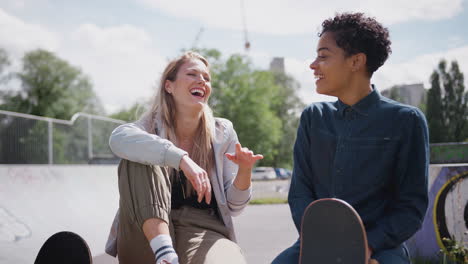 two female friends talking and laughing in urban skate park