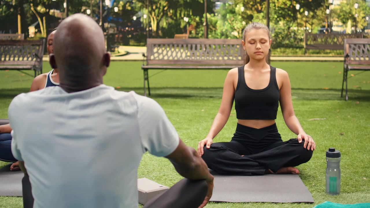 Women meditating with eyes closed during outdoor yoga class guided by instructor