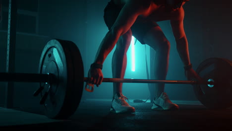 muscular fitness man doing push a barbell over his head in modern fitness center. functional training. snatch exercise. slow motion color led light saturated bright colors