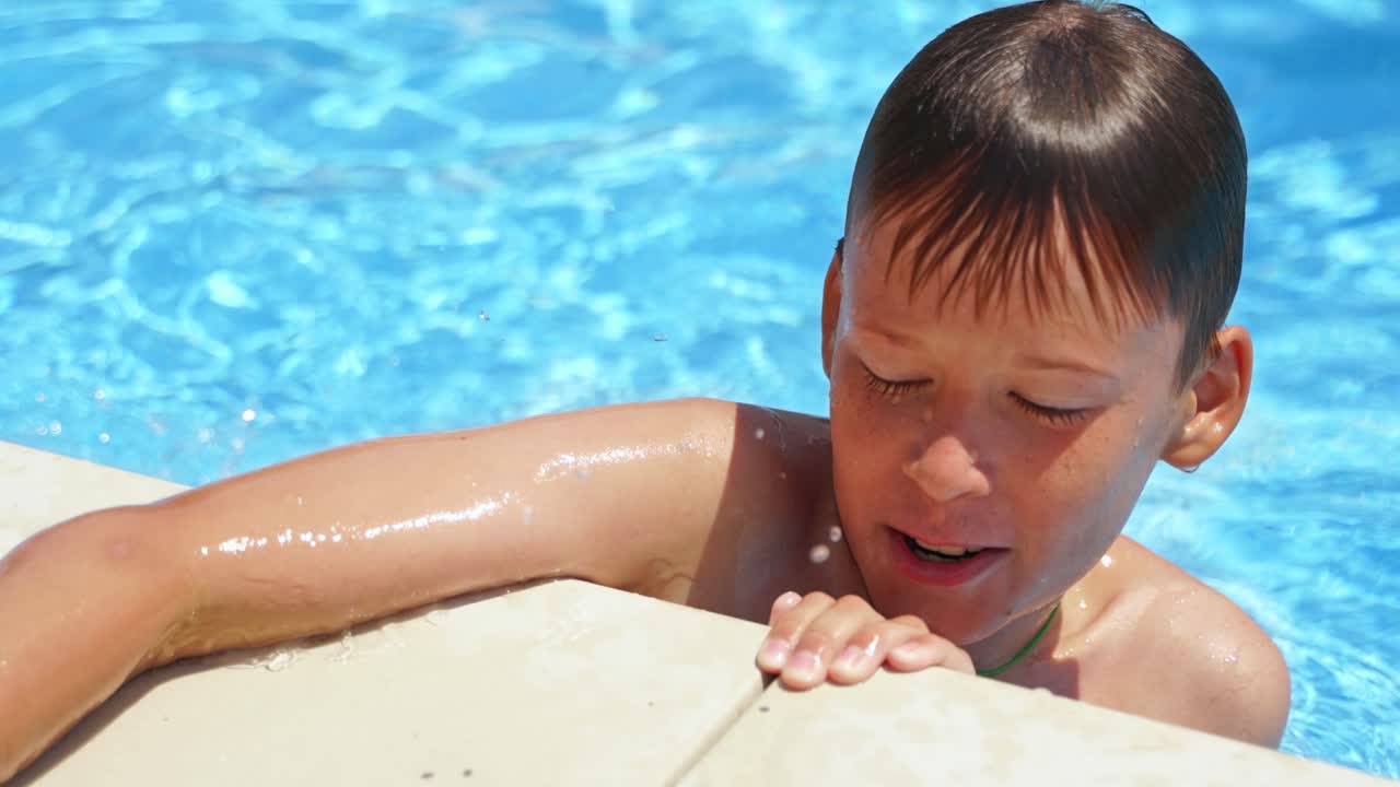 Close-up boy's face in the pool. Curious child having fun in the swimming pool outdoors. Summer vacation.
