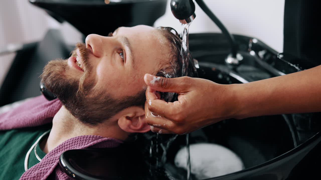 Mand får vasket og skyllet hår i en barbersalon.