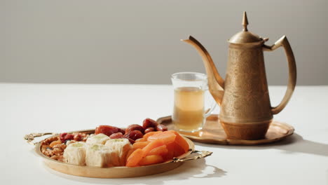 a hand reaching for sweets on a gold tray with tea