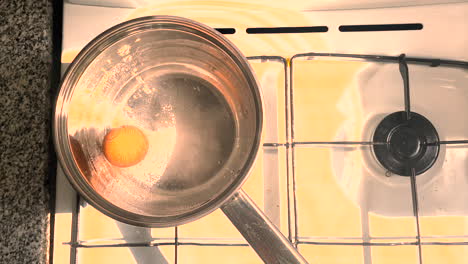 The egg is boiled in a saucepan on a gas stove, the water boils slowly