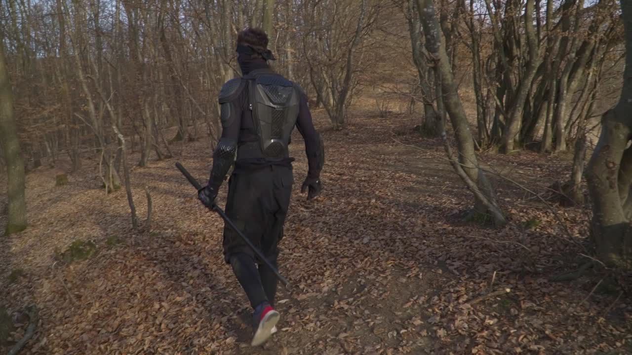A mysterious ninja in black tactical gear moves silently through a leaf-covered forest. Perfect for action, martial arts, samurai, and cinematic projects.