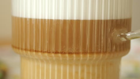 close-up of a latte in a striped glass cup