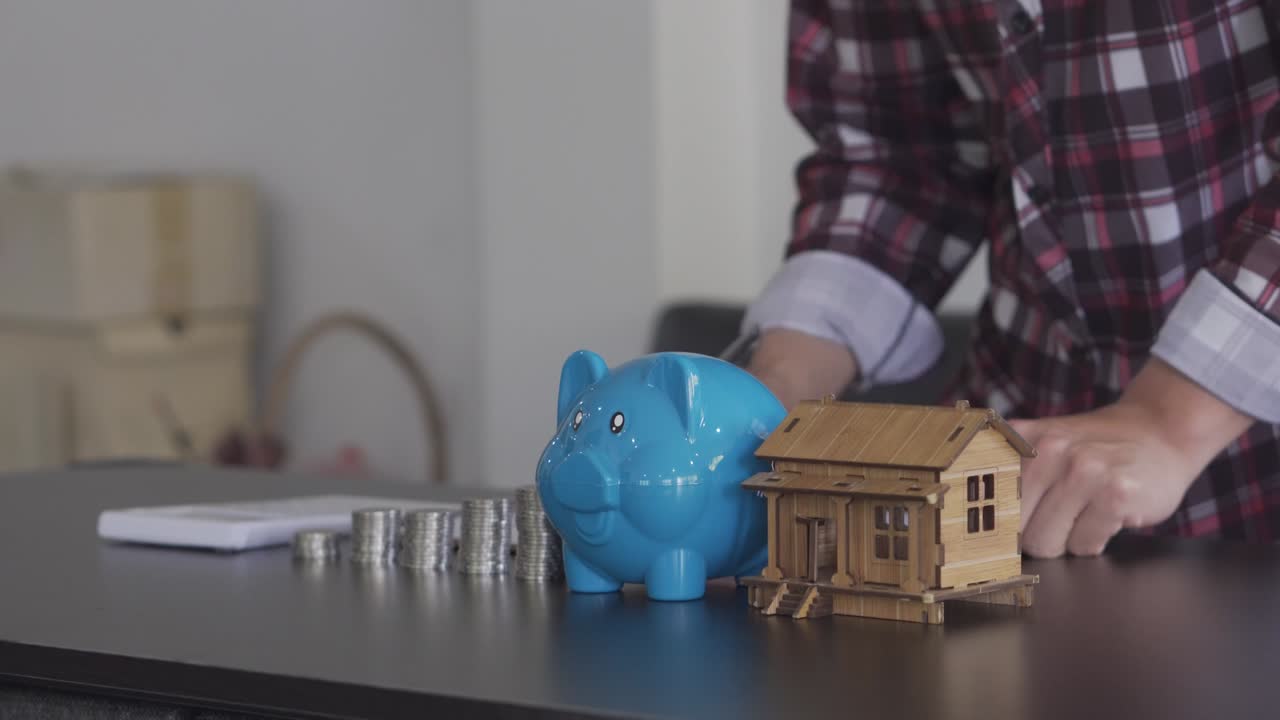 joven contando monedas en una alcancía para ahorrar dinero, comprar una casa, conceptos financieros y económicos. cuentas de gastos mensuales y reembolsos de deudas usando calculadoras y documentos fiscales en casa.