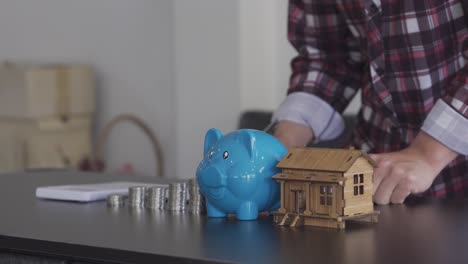 young man counting coins in a piggy bank to save money, buy a house, financial and economic concepts. monthly expenditure accounts and debt repayments using calculators and tax documents at home.