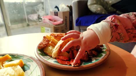 baby's hand reaching for fried chicken and fries