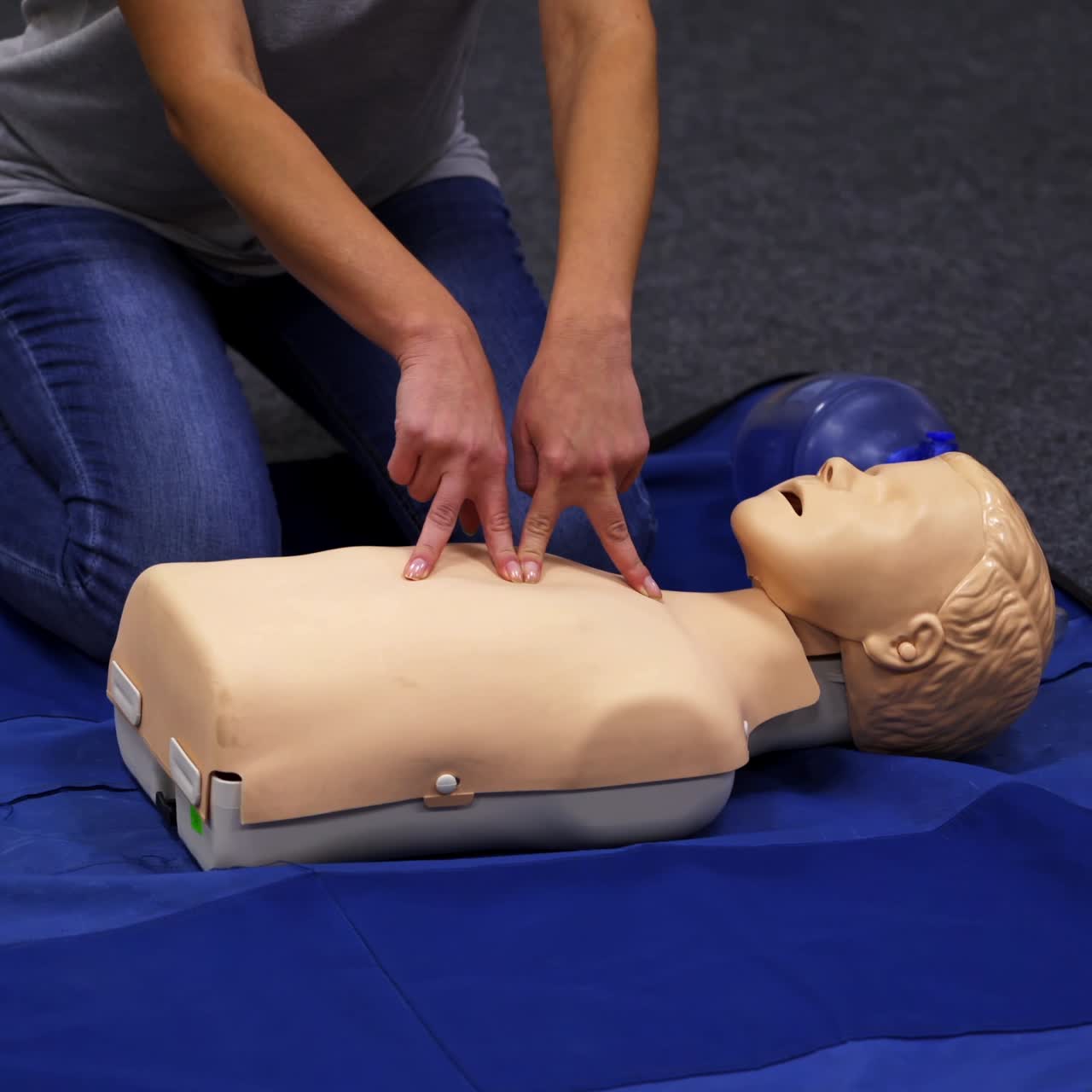 Giving first aid CPR on a dummy. Female trainer demonstrates cardiopulmonary reanimation. Training on a mannequin to save life.