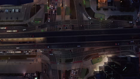 Aerial-birds-eye-overhead-top-down-descending-view-of-traffic-in-night-city.-Vehicles-on-multilevel-and-multilane-intersection.-Warsaw,-Poland