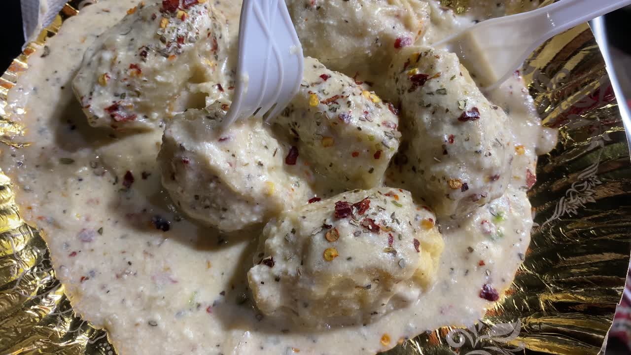 un hombre que sostiene un plato de momo afgano servido con salsa blanca cremosa o salsa bechamel que se vende en kolkata