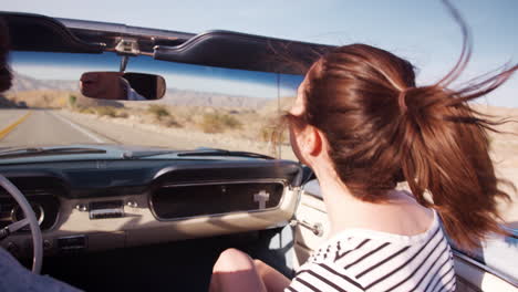 Young-white-couple-in-open-top-car-on-a-road-trip,-close-up