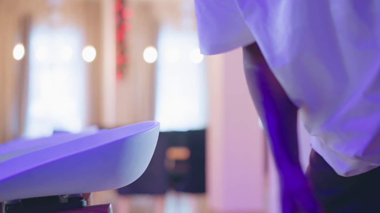 Close-up of a person s hand adjusting bar stools in a modern lounge with purple lighting, festive decor, and stylish seating. A scene of hospitality staff setting up the bar area for service