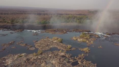 se forma un arco iris brillante en la niebla en una antena baja en el labio de las cataratas victoria.