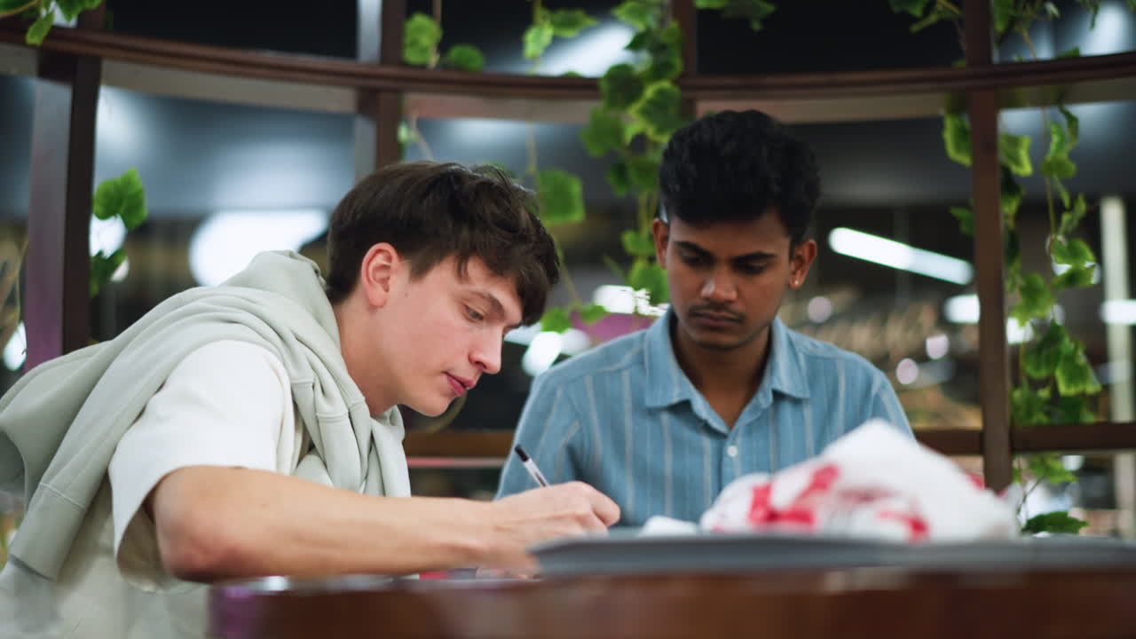 Indoor night scene overlooking city lights through window soft ambient glow illuminating wooden table with tray of assorted snacks on plate beside cups and cutlery creating cozy relaxed evening mood