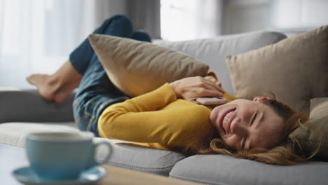 happy woman receiving message on mobile phone laying chilling cozy sofa closeup
