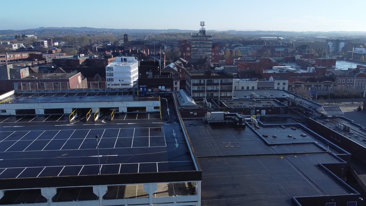 Overhead aerial view above city multi storey car park quiet British urban public streets at sunrise pull back