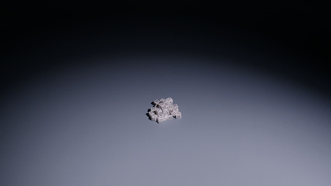 Slow-motion wide shot as large white die falls onto pile of tiny dice in middle of screen and dice shoot out