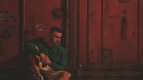 male boxer rests sitting next to the punching bag