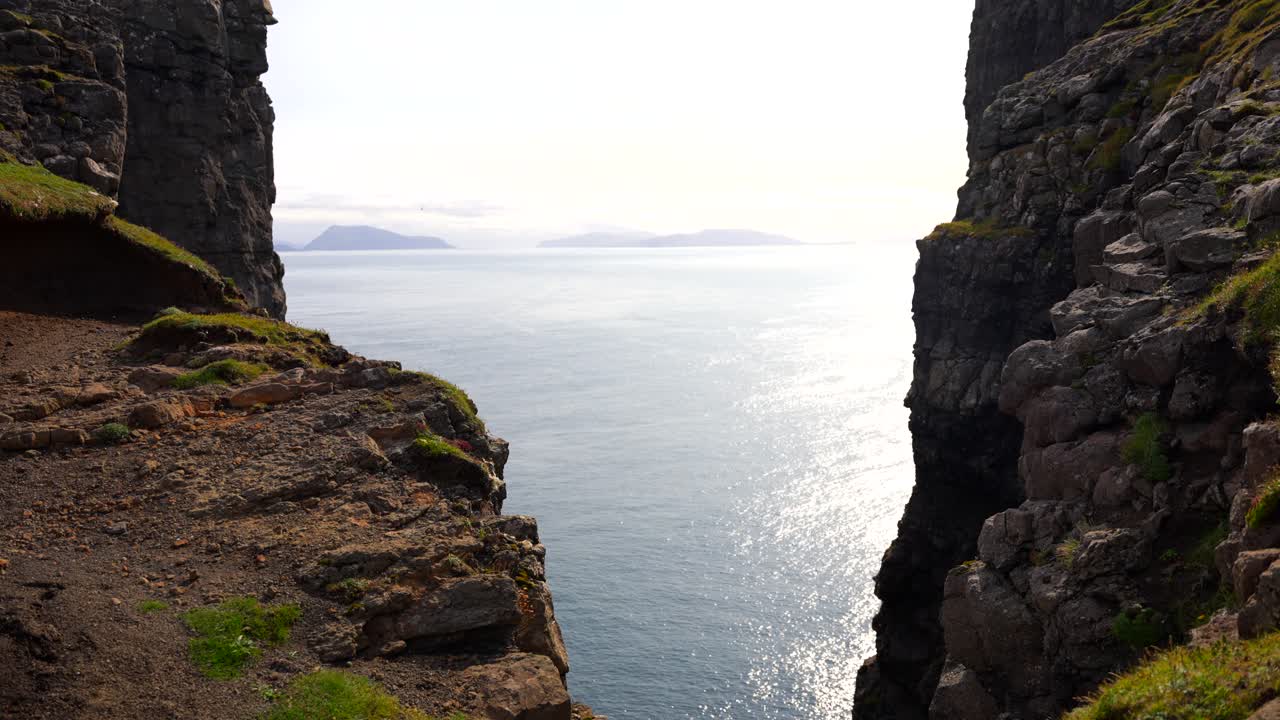 fotografía estática del reflejo del sol en el océano atlántico entre los acantilados de las montañas rocosas en la isla de vagar, islas feroe