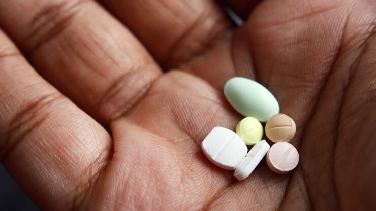 A close-up of a hand holding various pills.