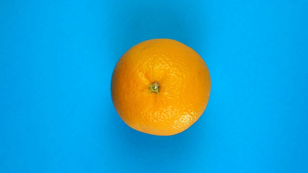 Topbillede af langsomt roterende appelsin på blå baggrund isoleret