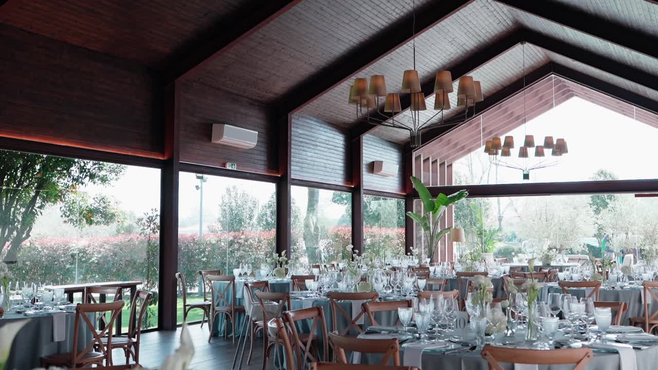 sunlit glass hall with banquet tables prepared for formal wedding reception