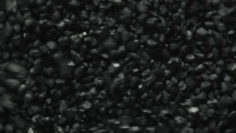 macro shot of black coal stones shaking and moving forward through vibrations of sound