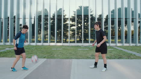 two girls training soccer ball passes on the street