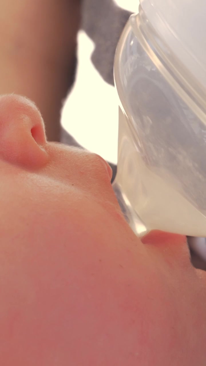 Tremåneders baby drikker vand fra flasken udendørs