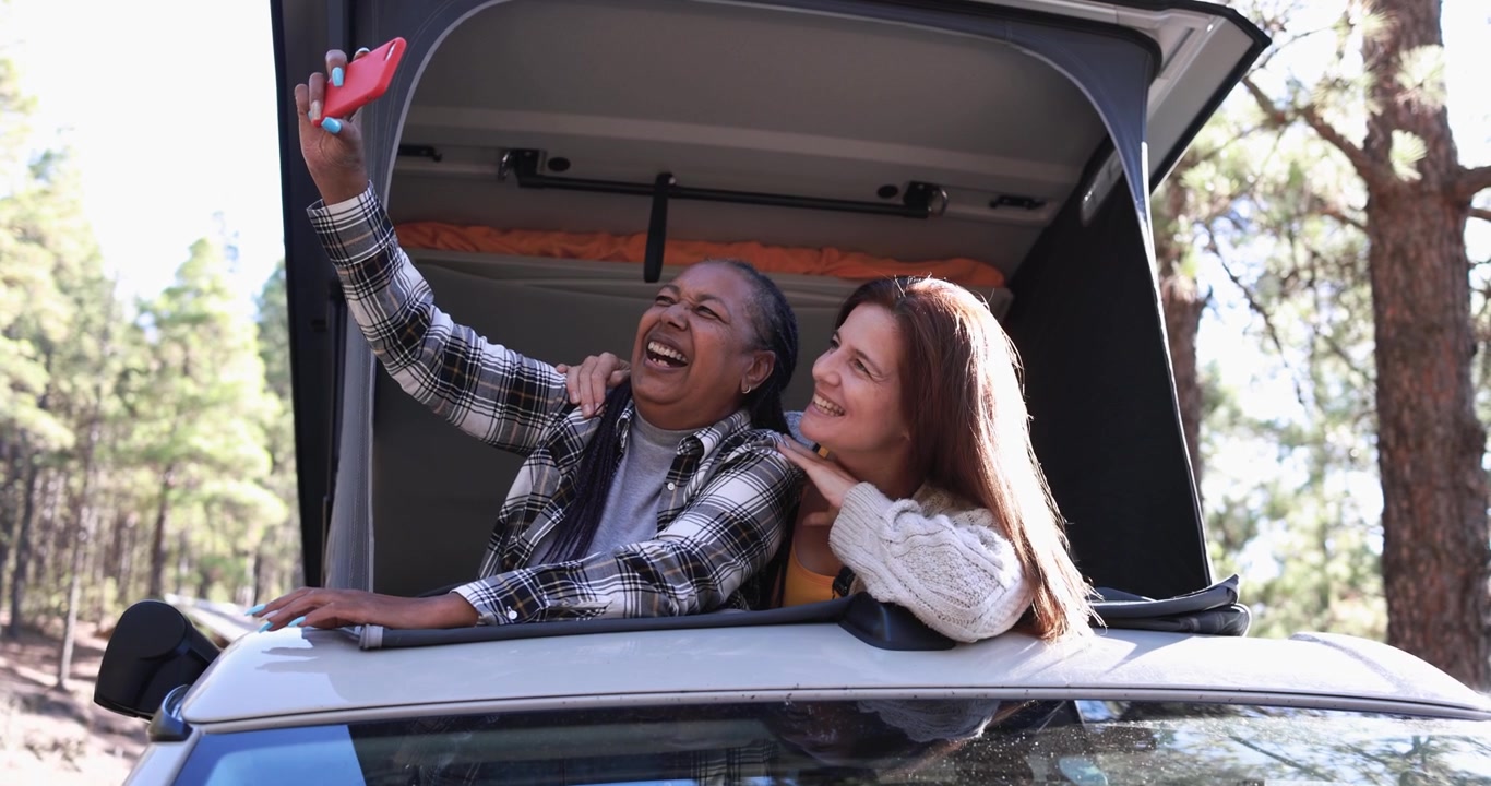 Due donne che si scattano un selfie dal tetto di un camper.