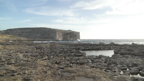 caminando hacia la roca fungosa en la meseta de piedra cerca de la ventana azul en la isla de gozo
