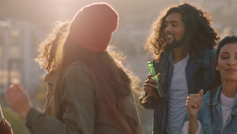 multi ethnic friends dancing celebrating on rooftop at sunset enjoying party weekend having fun socializing hanging out drinking alcohol