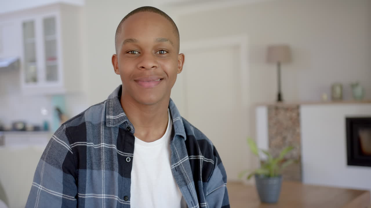 Portrett av en glad afroamerikansk mannlig tenåring med kort hår hjemme, sakte film