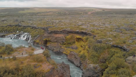 Hraunfossar,-Aussichtsplattform-Mit-Touristen,-Die-Die-Wasserfälle-Beobachten,-Die-Von-Bächen-Gebildet-Werden,-Die-Wasser-Strömen