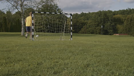 un niño patea la pelota hacia la portería, pero hay un desgarro en la red de la portería, por lo que la pelota rueda a través de la red