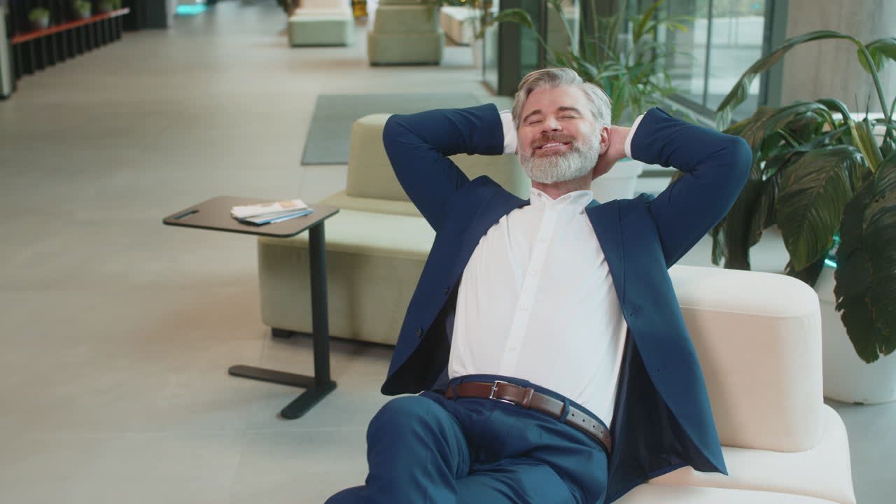 Caucasian businessman taking break leaning on couch after working celebrating success at hotel lobby