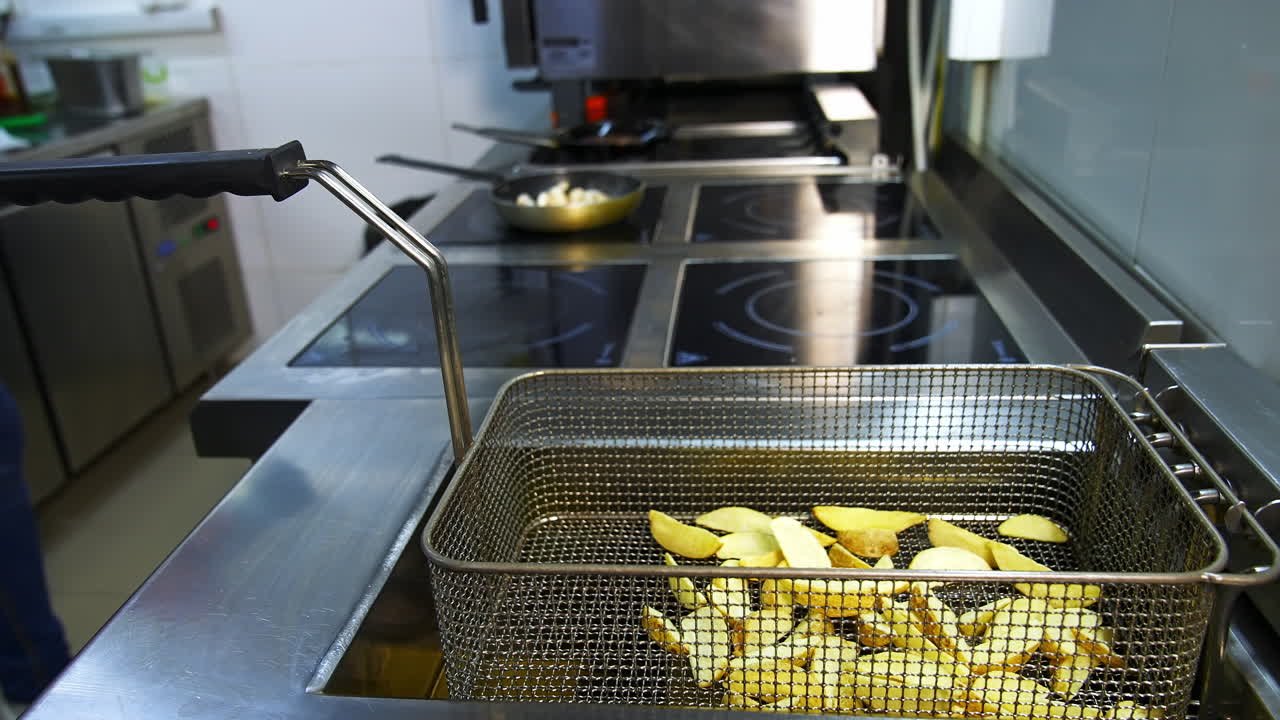 Cooked crispy potato in deep fryer. Golden potato pieces ready to eat. Deep fryer in the restaurant kitchen.