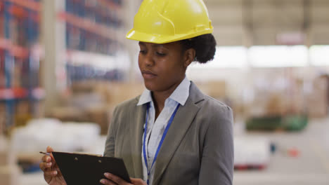 Retrato-De-Una-Trabajadora-Afroamericana-Con-Casco-Y-Sonriendo-En-El-Almacén