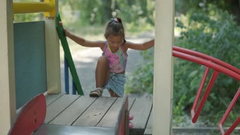 pregnant mother watching daughter play on slide at playground