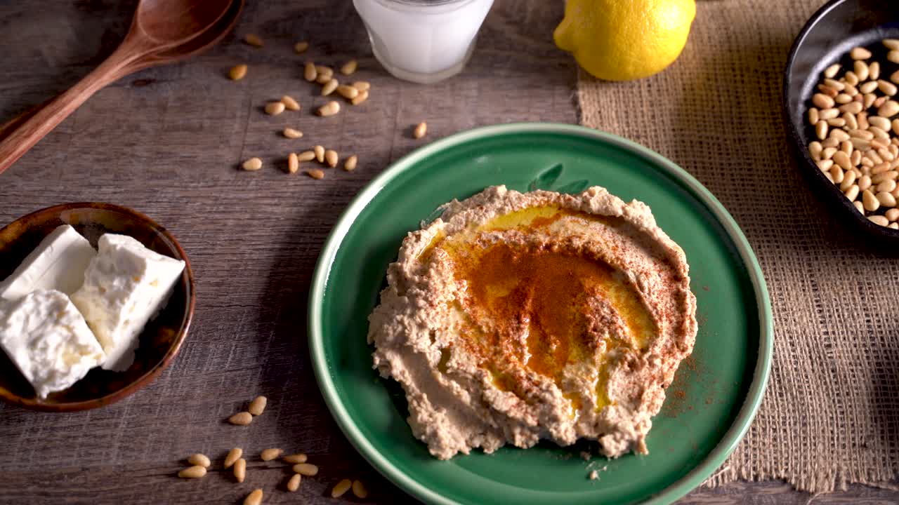 deslizamiento de alto ángulo a la izquierda de la comida del medio oriente untada con hummus, piñones, limones, aceitunas, get y ouzo o arak