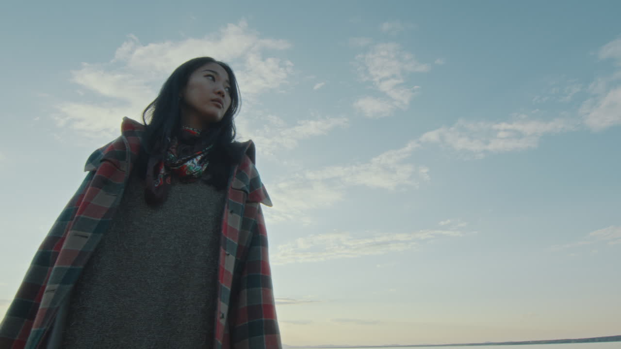 해가 지는 동안 호수변에 서서 주변을 둘러보는 등불을 든 젊은 여성