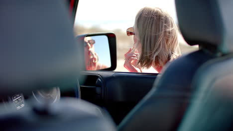 caucasian woman checks her phone in a car on a road trip