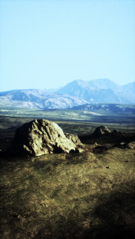 a vast landscape with a single rock in the foreground and mountains in the distance