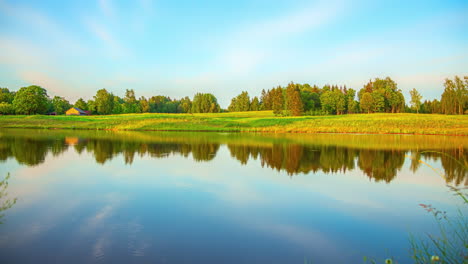a colourful time lapse reveal shot of a lake by a forest from dawn to dusk